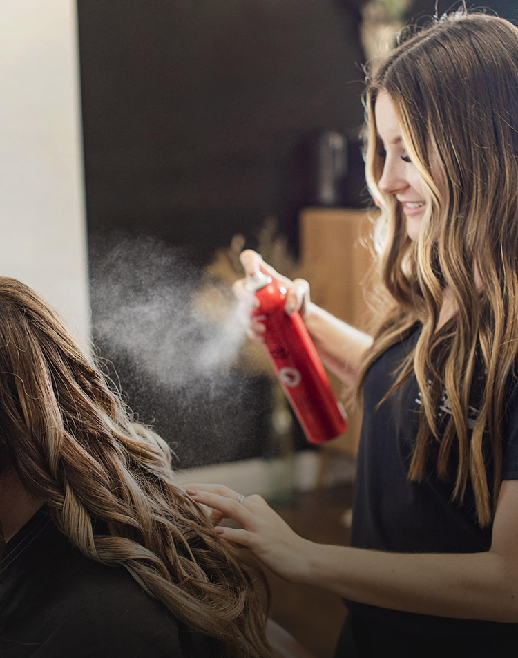 Karol York spraying hairspray on a client's hair