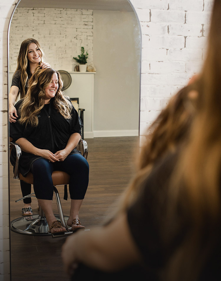 Karol York posing with a salon client in a mirror
