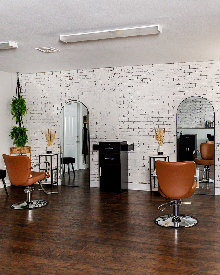 Two salon chairs, arched mirrors, and stylists stations at With a Kay Salon